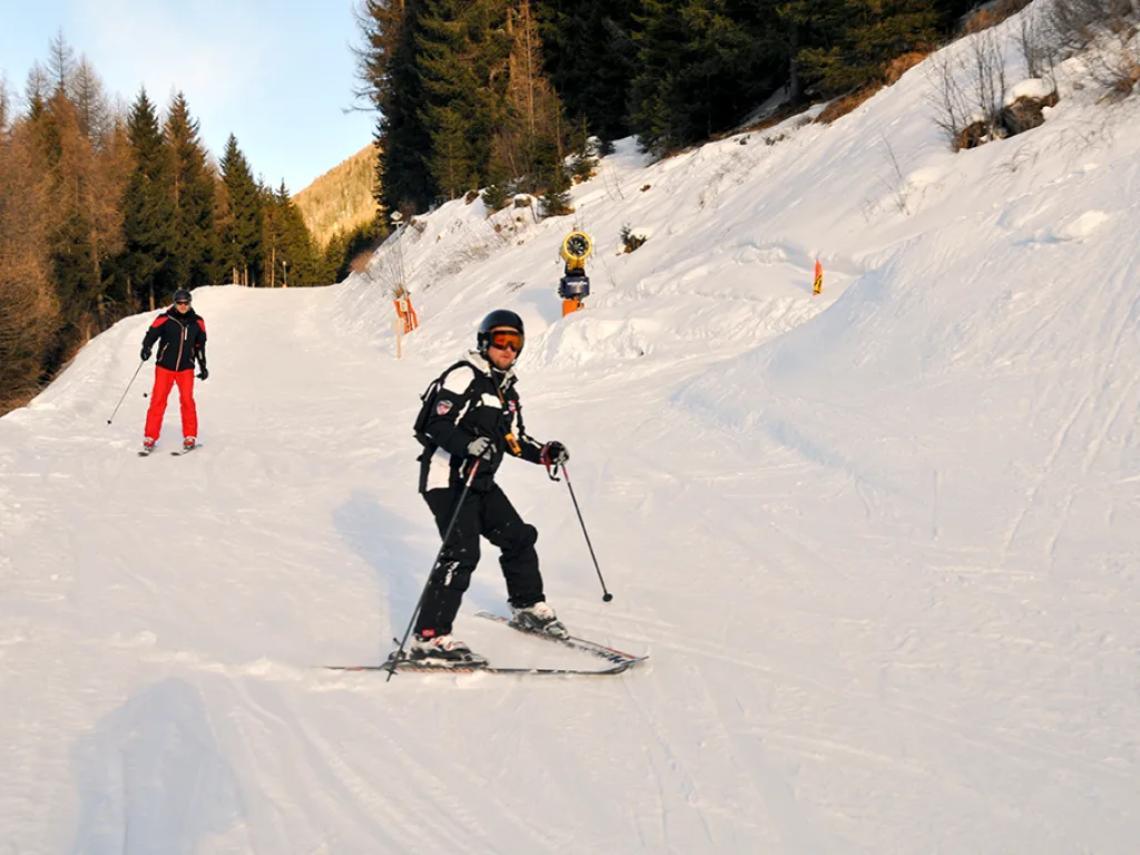 Skifahrer auf der Piste im Abendlicht.